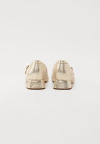 Goldene metallische Schuhe mit niedrigen Absätzen und strukturiertem Finish. Rundkopfdesign und kleine Schnallenakzente. Einfarbig mit minimalen Verzierungen.