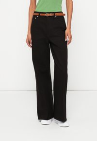 Μαύρο τζιν με φαρδιά πόδια κατασκευασμένο από ανθεκτικό ύφασμα, με καφέ δερμάτινη ζώνη, ασημένια μεταλλικά στοιχεία και μπροστινές τσέπες. Ομαλή υφή και καθαρό σχέδιο.