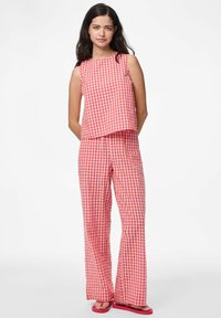 Sada bezrukoého topu a kalhot se širokými nohavicemi v červenobílém kostkovaném vzoru, vyrobená z lehkého materiálu, s volným střihem a neformálním designem.