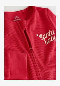 Monos rojo de tela acanalada para bebé con cremallera frontal, que presenta un bordado de "santa baby" y un pequeño diseño de gorro de Santa.