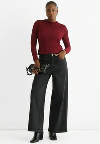 Black wide-leg jeans paired with a textured burgundy sweater. The outfit includes a sleek black handbag and black ankle boots.