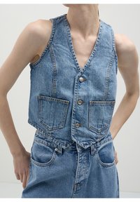 Jeansväst med V-ringning, ljusblå färg, med två framfickor, tre knappar och en kortad design.