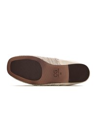 Zapato de lona beige sin cordones con una parte superior de tejido texturizado, detalles en cuero suave y una suela de goma marrón con un sutil patrón de tracción.