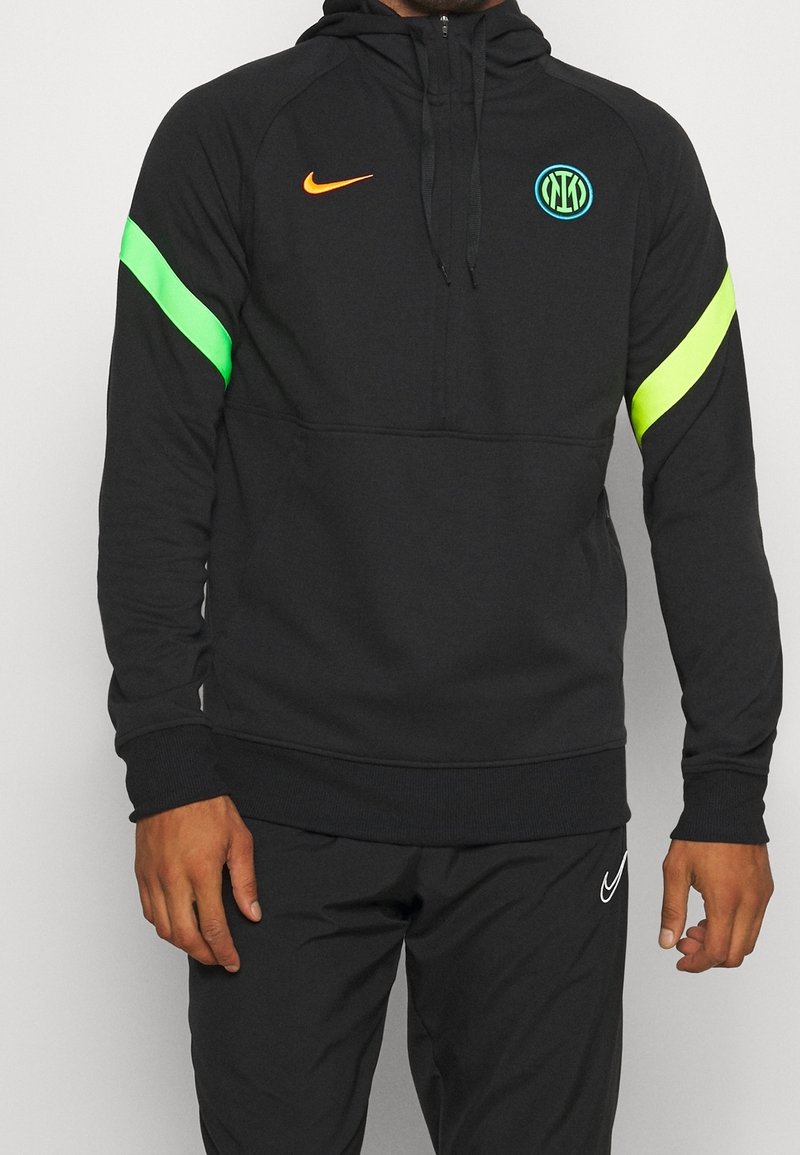 Sweat-shirt à capuche noir avec fermeture éclair quart, présentant une bande verte et jaune sur les manches et un logo circulaire sur la poitrine.