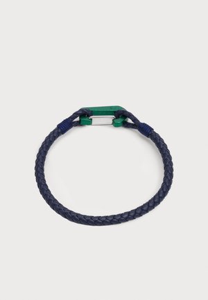 Navy braided leather bracelet with green metal clasp and blue accents. Features a rounded shape and textured finish.