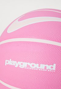 Basket-ball rose avec une surface texturée, arborant un logo swoosh blanc et une marque "playground" en blanc, conçu pour une utilisation en extérieur.