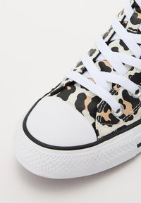 Beige, mustril ja virsikukarva tigermustriga kangast tennisetossud. Omavad valgeid paelu, kummist varbakatet ja musta äärist.