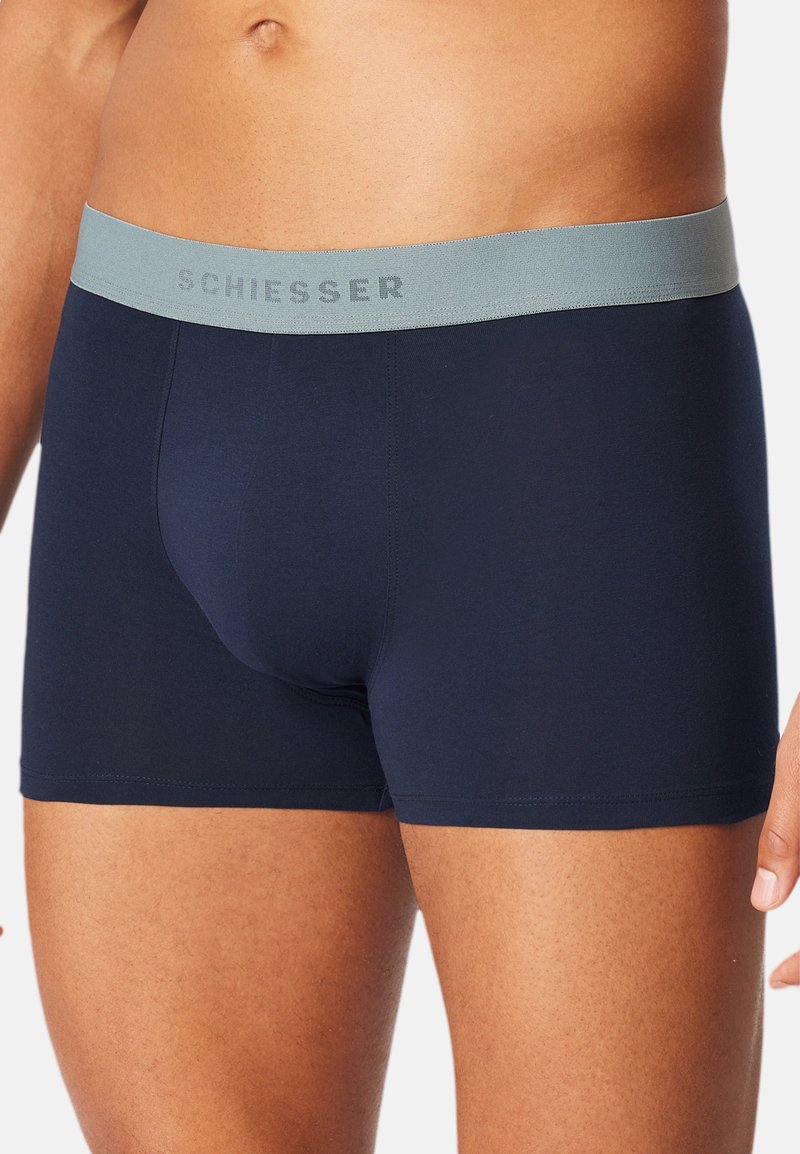 Marineblaue Boxer Shorts mit einem weichen, elastischen grauen Bund, der den Text "SCHIESSER" in einem dezenten Ton trägt. Glatte, figurbetonte Stoffqualität.