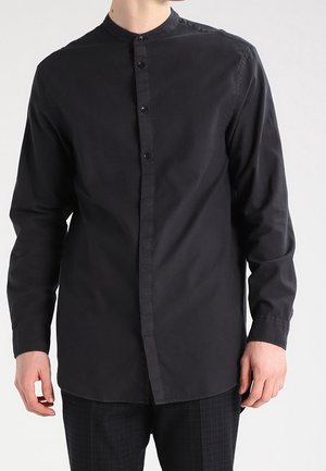 Chemise noire à manches longues avec un col mandarin, présentant une fermeture à boutons sur toute la longueur et un tissu lisse et léger. Sans motifs ni accents.