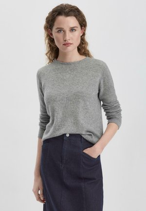 Grijze gebreide trui met een ronde halslijn en lange mouwen, gecombineerd met een donkerdenim rok met voorzakken en een knoopsluiting.