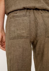 Bordeaux linnenbroek met twee achterzakken, gemaakt van textiel met een gestructureerde stof en een relaxed fit. Stiksels zijn zichtbaar langs de randen van de zakken.