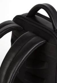 Musta reppu, jossa on tekstuurilla varustetut nahkahihnat, vetoketjullinen yläosa, pehmustettu selkäpaneeli ja kestävät kangas yksityiskohdat.