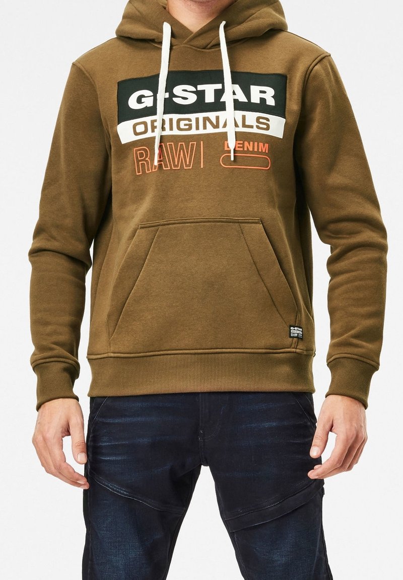 Sudadera G-Star Raw en verde oliva con cordones blancos, gran texto de marca en negro y naranja, bolsillo frontal tipo canguro, dobladillo y puños acanalados.