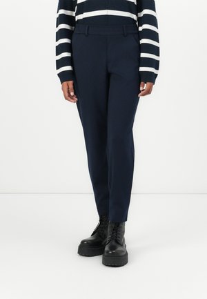 Navy tailored pants with a smooth texture, slim fit, and belt loops, paired with black lace-up combat boots. Striped sweater visible on upper body.