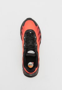 Nike Air Max en rouge et noir, avec une tige texturée, un système de laçage et une unité de coussin d'air visible dans la semelle.