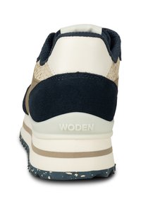 Blå och beige sportskor med mocka- och mesh-material, vadderad krage, och en vit gummisula med ett texturerat greppmönster.