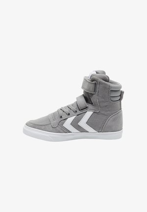 Baskets montantes grises avec des bandes chevron blanches, fermeture à lacets et doubles bandes Velcro sur une semelle en caoutchouc blanche.