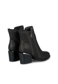 Zwarte leren enkelboots met zilveren piramide-studs, zijritsen en grove hakken met metallic accenten. Glad oppervlak, strakke pasvorm.