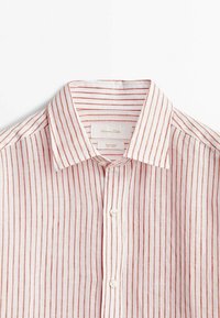 Chemise en lin blanc avec des fines rayures verticales couleur rouille, col classique et boutons blancs sur le devant.