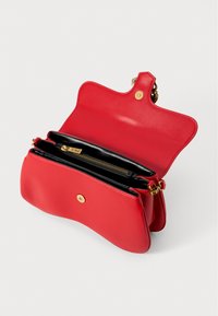 Sac à main en cuir rouge avec un design structuré et incurvé. Doté d'une fermeture à pression dorée, d'une doublure intérieure noire et d'un compartiment zippé.