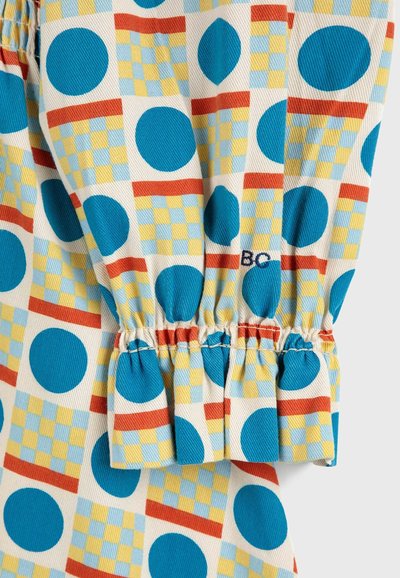 Camicia multicolore con cerchi blu e motivi a quadretti gialli. Realizzata in tessuto testurizzato con maniche arricciate e dettagli ricamati.