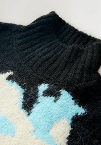 Schwarzer Wollpullover mit hohem Rippkragen, ausgestattet mit einem Farbblockdesign in Hellblau und Creme, das ein strukturiertes Strickmuster zeigt.