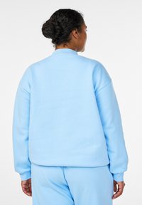 Lichtblauwe trui, zachte textuur, comfortabele pasvorm, geribbelde boorden en kraag, met een eenvoudig stikselpatroon, zonder zichtbare logo's of details.