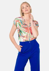 Kleurrijke korte mouw top met een bloemenpatroon, voorzien van een v-hals en sleufdetail, gecombineerd met blauwe hoge taille broek.