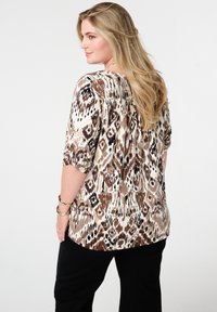 Lichte blouse met dierenprint in beige, bruin en zwart. Heeft een ontspannen pasvorm, 3/4 mouwen en een geplooide achterkant.