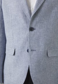 Gai zils linu bleizers ar teksturētu apdari. Iespējas: divas frontālās kabatas, divi pogas un piegādāts siluets ar maigu spīdumu.