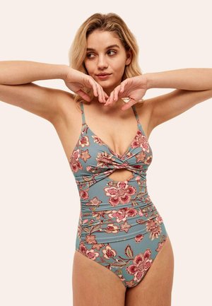 Maillot de bain bleu clair avec un motif floral rose, présentant un détail noué à l'avant et une découpe. Fines bretelles ajustables, tissu texturé.