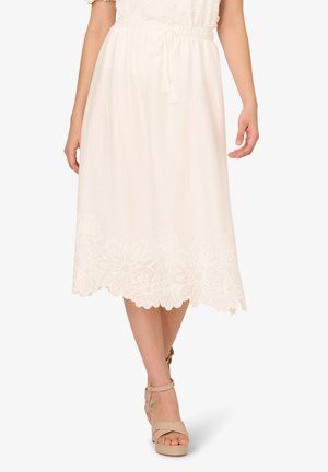 Jupe midi blanche avec broderie florale à l'ourlet, en tissu léger, taille élastique avec cordon de serrage, portée avec des sandales à plateforme beiges.