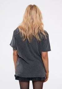 Dark gray oversized t-shirt with a relaxed fit, short sleeves, and a faded texture. Detailed stitching and a slightly dropped shoulder design.