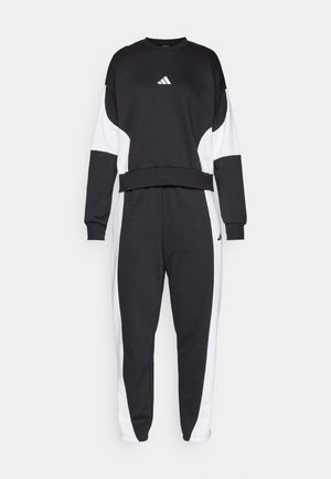 Survêtement noir et blanc composé d'un col rond, de manches longues et de pantalons fuselés avec des panneaux latéraux et un logo brodé sur la poitrine.