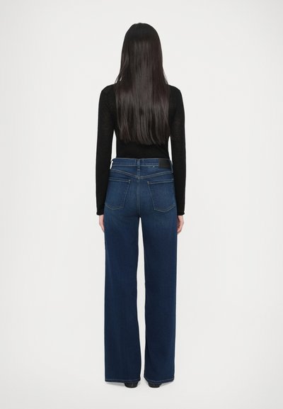 Široke modre kavbojke iz jeansa z visokim pasom, z dvema zadnjima žepoma in črnim usnjenim trakom na pasu, brez vidnih vzorcev.