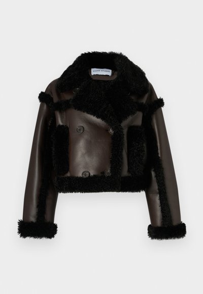 Cropped double-breasted jacket in dark brown leather with black shearling accents. Notable features include large buttons and a wide collar.