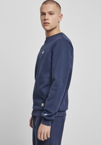 Marineblå sweatshirt med rund halsudskærning, ribbede manchetter og et lille logo på brystet. Fremstillet af blødt, tekstureret stof.