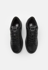 Baskets en cuir noir avec un bout arrondi, un design à lacets, un col rembourré et un logo sur la languette. Texture lisse avec peu de détails.