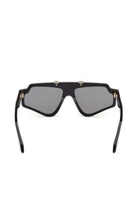 Occhiali da sole neri over-size con lenti angolari grigio scuro e una struttura superiore prominente, mostrati frontalmente su uno sfondo bianco.