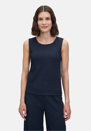 Haut sans manches bleu marine avec un col rond, en tissu texturé et d'une coupe ample, porté avec un pantalon bleu marine assorti.