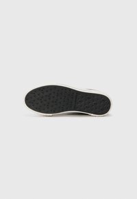 Sole in gomma nera con motivo testurizzato per la presa, bordo in gomma bianca, con nome del marchio inciso sul fondo.