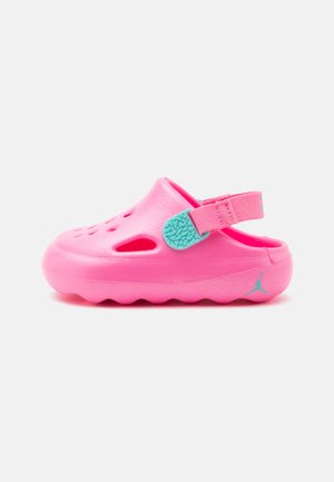Sabot rose vif à enfiler avec des trous de ventilation et une bride turquoise réglable sur fond blanc.