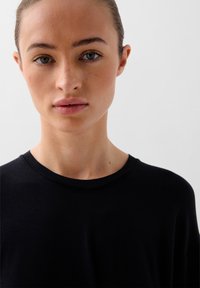 T-shirt nero con scollo rotondo, texture morbida e vestibilità rilassata. Il tessuto appare liscio con dettagli minimi e senza motivi visibili.