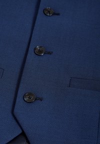 Modra žakardasta blazer s tremi črnimi gumbi in elegatnim detajlom žepa. Material prikazuje subtilen ribji vzorec.