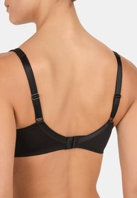 Czarny stanik z gładkiego materiału, z regulowanymi ramiączkami i zapięciem na haftkę z tyłu. Posiada delikatne przeszycia wzdłuż brzegów.