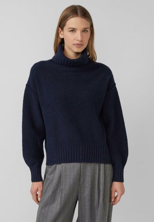 Granatowy, oversize sweter z wysokim ściągaczem i ściągaczem u dołu. Teksturowana tkanina, opadające ramiona i długie rękawy.