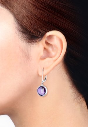 Silberne Ohrhaken mit einem runden, facettierten lila Edelstein. Der Edelstein ist in einer glatten, kreisförmigen Silberfassung eingelassen.
