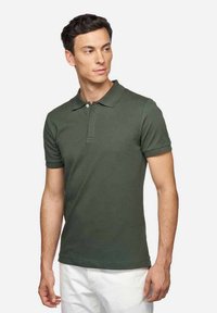 Polo shirt verde scuro in cotone, con colletto classico, maniche corte e pattina con tre bottoni. Design semplice e aderente.