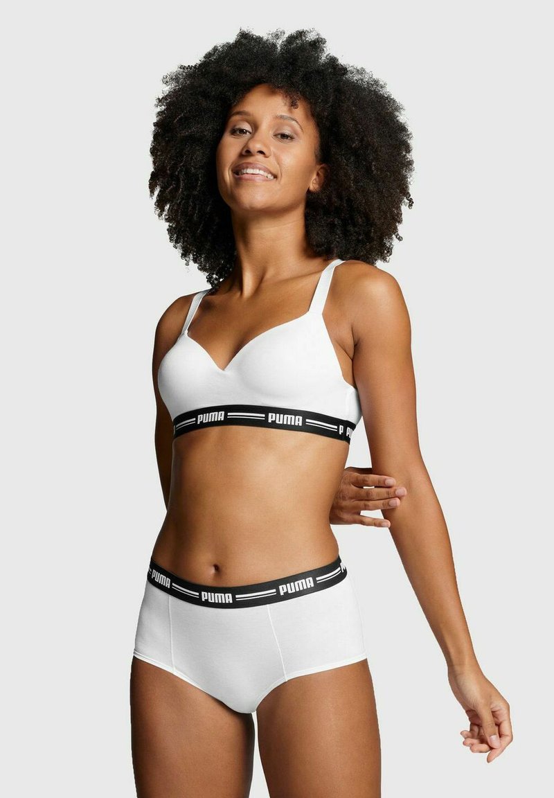 Weißer nahtloser Bh mit verstellbaren Trägern und schwarz gebrandetem Unterband, kombiniert mit weißen hoch taillierten Slips mit passendem schwarzen Bund.