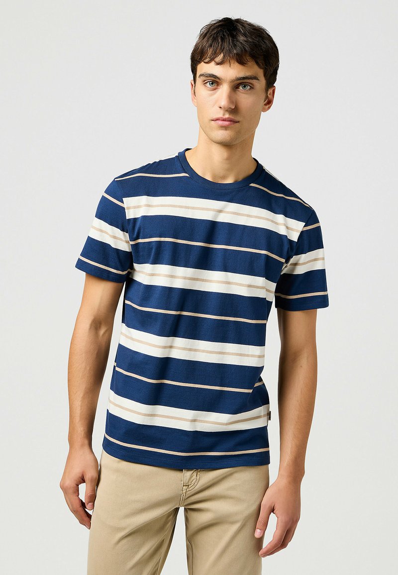 Camiseta de rayas de marino con rayas horizontales en blanco y beige. Mangas cortas, diseño clásico de cuello redondo, textura suave y ajuste casual.
